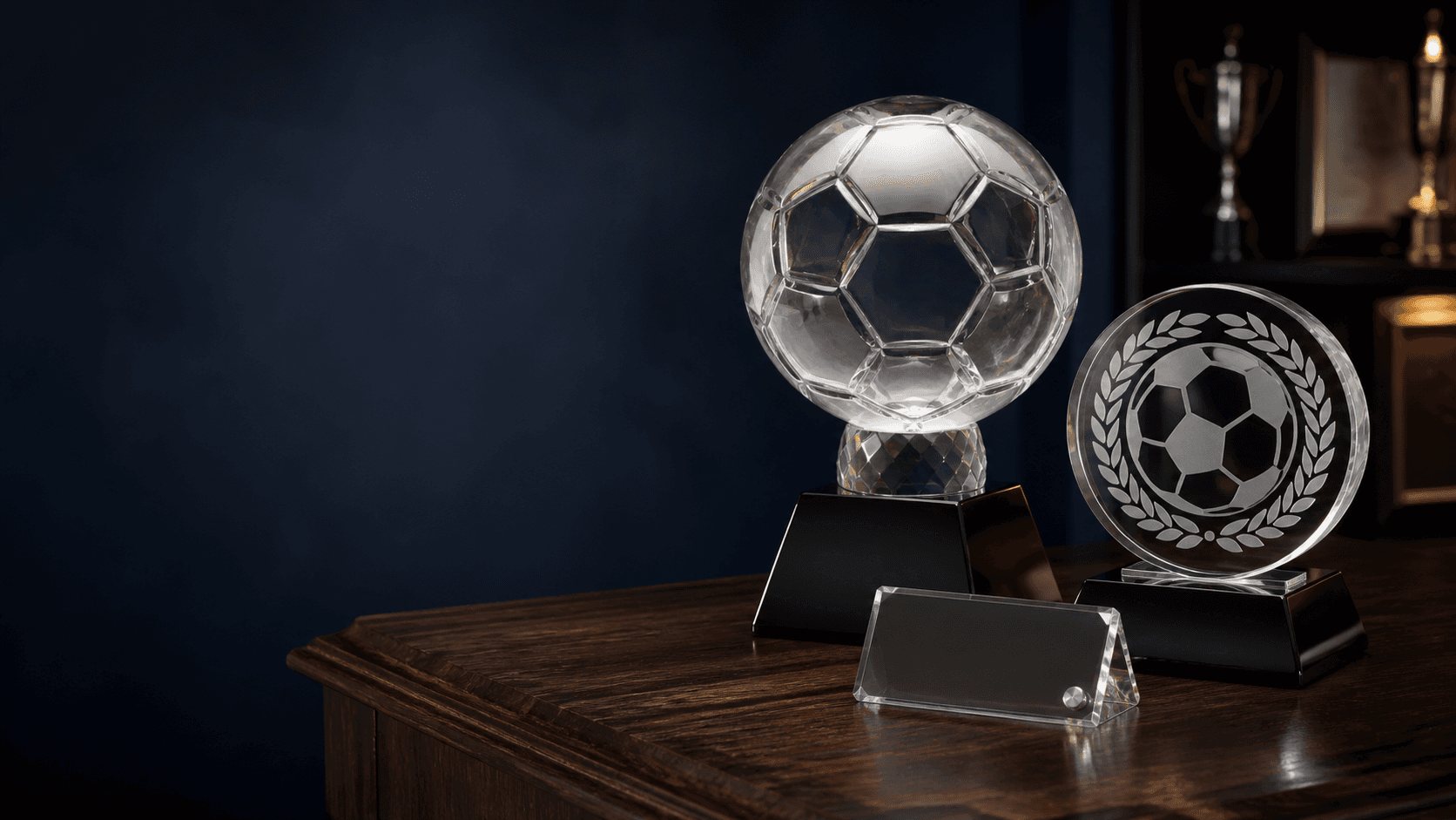 Clear crystal football trophies arranged on a walnut display table in a heritage workshop